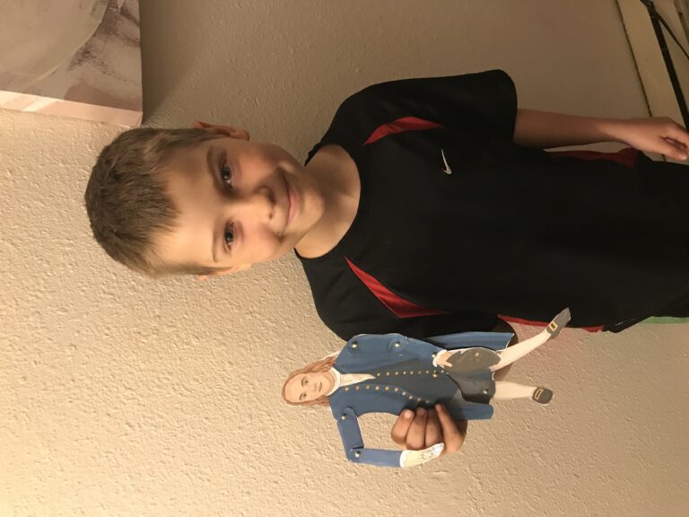 my 9-year-old son standing up and holding a paper doll of benjamin franklin